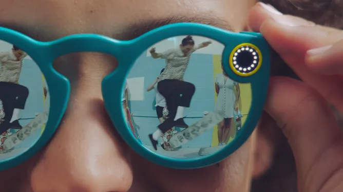 فردی که در روز از عینک های دوربین Snap Spectacles در فضای باز استفاده می کند.